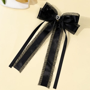 Détail d'un nœud papillon élégant en résille noire avec strass cœur et longs rubans fins