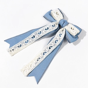 Détail du nœud à cheveux en jean bleu clair avec dentelle cœur et surpiqûres marron