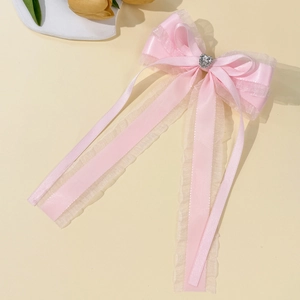 Barrette à cheveux rose avec nœud en maille et strass en cœur sur fond beige chaud