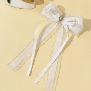 Détail de la pince à cheveux avec ruban en dentelle blanche et strass étincelant en forme de cœur