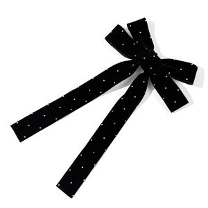 Macro detail of black velvet bow hair clip with sparkling silver rhinestone polka dots