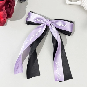 Close-up of a purple and black bow hair clip with Just for you text on silk ribbon