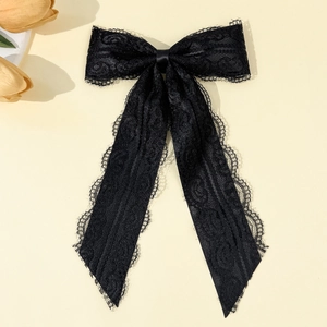 Detail of elegant black lace bow brooch with long ribbons and floral lace patterns