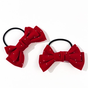 Close-up of red velvet bow hair ties with sparkling rhinestones on a white background