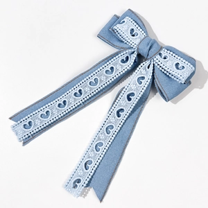 Détail du nœud papillon en denim bleu avec dentelle cœur blanche et longs rubans