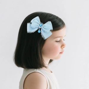 Blue mesh bow hair clip with jewel detail worn by child model on side hair
