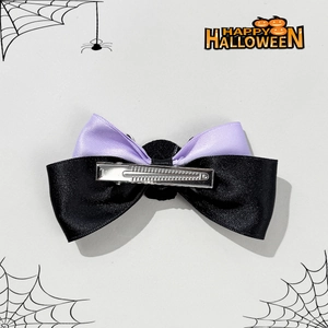 Detail of Halloween bow hair clip featuring purple ribbons and a silver metal duckbill clip