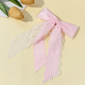 Detail of pink layered lace bowtie brooch with delicate floral patterns and satin ribbons
