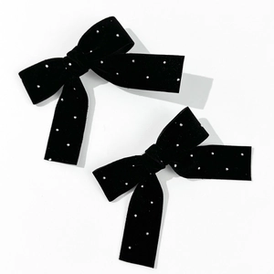 Detail of two black velvet bow hair clips with sparkling rhinestones on white background