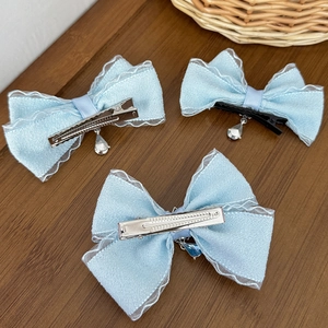 Three-piece light blue chiffon bow hair clips with crystal pendants on wooden background