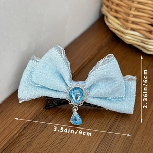 Detailed view of light blue bow hair clip with pear-shaped gemstone and silver base