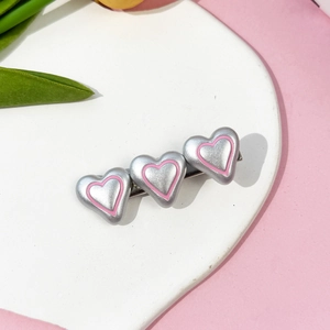 Vue détaillée de la pince à cheveux cœur rose sur plateau blanc avec décor floral