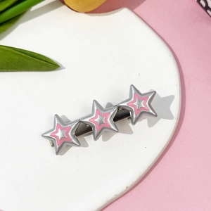 Gros plan de barrettes à cheveux roses à trois étoiles sur une assiette décorée