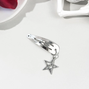 Barrette argentée avec pendentif étoile sur fond épuré avec des pétales rouges
