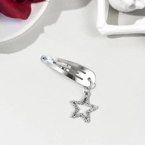 Détail d'une barrette étoile argentée avec zircons sur fond blanc et décor d'os