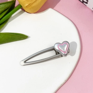 Gros plan d'une barrette à cheveux cœur rose sur une assiette en céramique