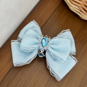 Detail of light blue bow hair clip with teardrop gemstone and vintage silver frame