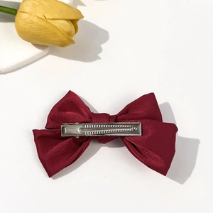 Elegant burgundy satin bow hair clip with metal alligator grip and smooth glossy texture