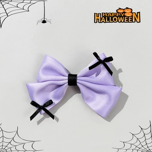 Close-up of Halloween purple satin bow clip with mini black ribbon and festive motifs