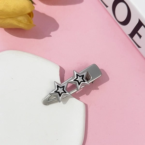 Detailed macro view of silver Y2K star hair clips featuring black inner layer on a white tray