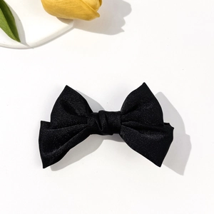 Close-up of black satin bow hair clip with shimmering texture on a clean white background