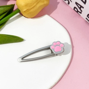 Détail d'une barrette à cheveux patte de chat argentée sur un plateau blanc élégant
