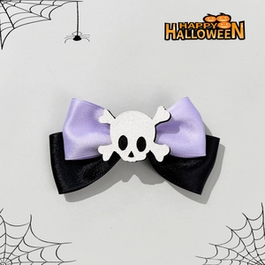 Detail of Halloween bow hair clip featuring a glittery skull on purple and black ribbons