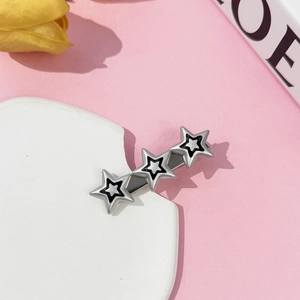Detailed macro shot of three silver Y2K star hair clips on a white stone display stand