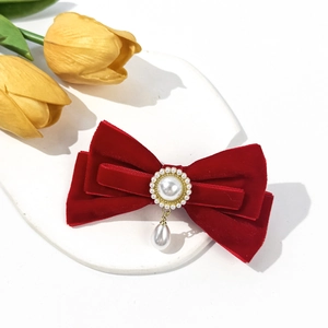 Close-up of red velvet bow hair clip with vintage pearls and elegant golden details
