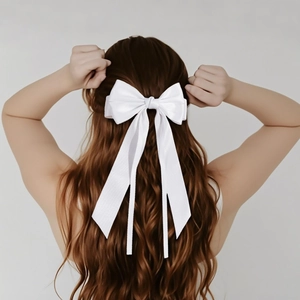Elegant large white satin bow hair clip with long ribbons on back of woman's head