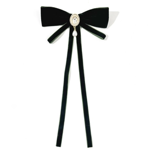 Detail of velvet bow brooch with an oval rhinestone center and a teardrop pearl pendant