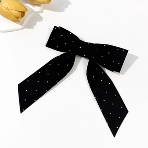Detailed view of elegant black velvet bow hair clip with sparkling white rhinestone accents