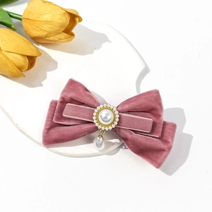 French vintage pink velvet bow hair clip with pearl pendant on a white marble display