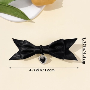Detailansicht der schwarzen Satin-Schleifen-Haarspange mit Herzanhänger und Maßen 12cm x 4,5cm