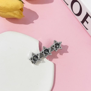 Detail of silver hexagram hair clip with dark crystals on an elegant marble surface