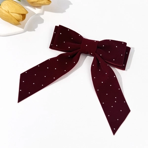 Detailed macro view of burgundy velvet hair bow with rhinestones and long elegant ribbons