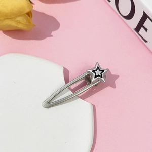 Close-up of Y2K style silver metal star hair clip with black border on a pink background