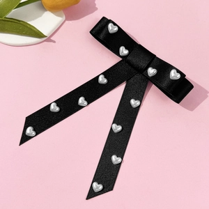 Detailed macro view of the black satin ribbon bow with silver heart-shaped pearl rivets