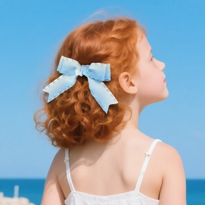 Detail of light blue layered ribbon bow hair clip with long tails on a girl with red hair