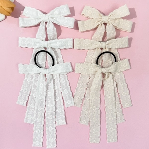 Elegante weiße und beige Spitzenbogen-Haarspangen mit langen Bändern auf rosa Grund