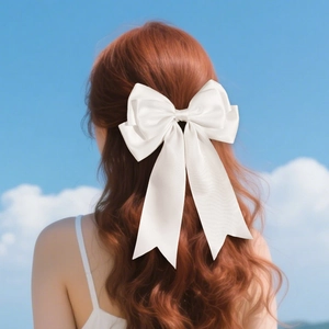 Detailed view of multilayered white satin bow hair clip with elegant long ribbons