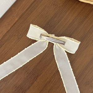 Elegant off-white bow hair clip with wavy ribbon texture and a silver metal alligator clip