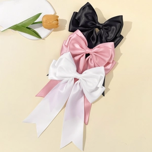 Three large satin bow hair clips in black, pink, and white with long elegant ribbons