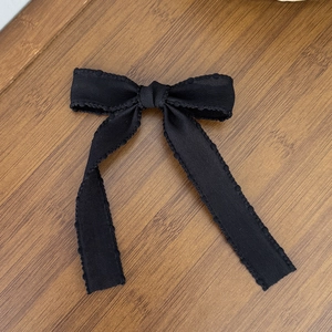 Detailed view of black ballet-style mesh bow hair clip with elegant scalloped lace edges