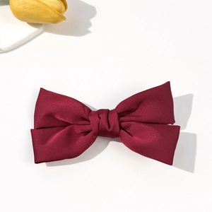 Close-up of a double-layered dark red satin bow hair clip with silk texture on white background