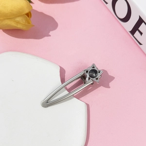 Detail of silver star hair clip with grey stone and white rhinestones on marble