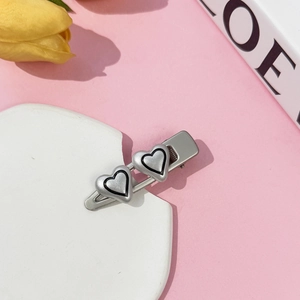 Close-up of Y2K style silver metal hair clip with double heart design on pink background