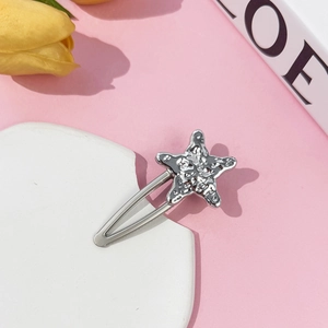 Detailed view of a silver starfish hair clip with liquid metal texture on pink background