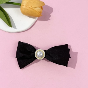 Detail of black satin bow hair clip with a center pearl and sparkling rhinestone trim