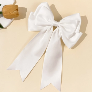 Detailed view of elegant large white satin bow hairclip with long hanging ribbons